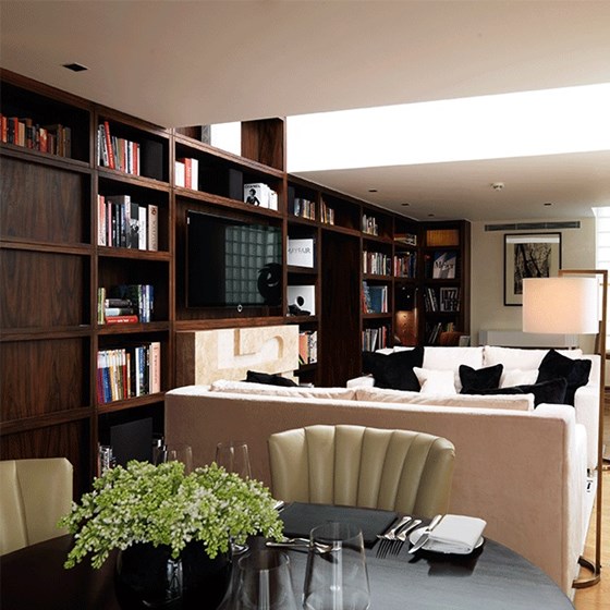 View of a part of the rooms of the Library Suite, with a large TV and comfortable furniture and lamps.