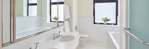 bath, sinks and vase of flowers on the window sill