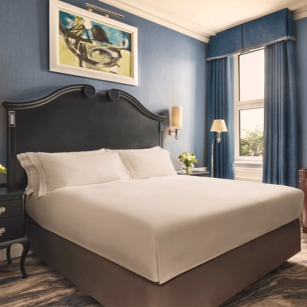Bright Superior Room with a dark wood bed, blue walls and curtains, bedside flowers and a desk by the window