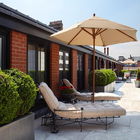 Two cream sun loungers and a parasol on Mayfair's largest terrace, which is part of the Terrace Suite.