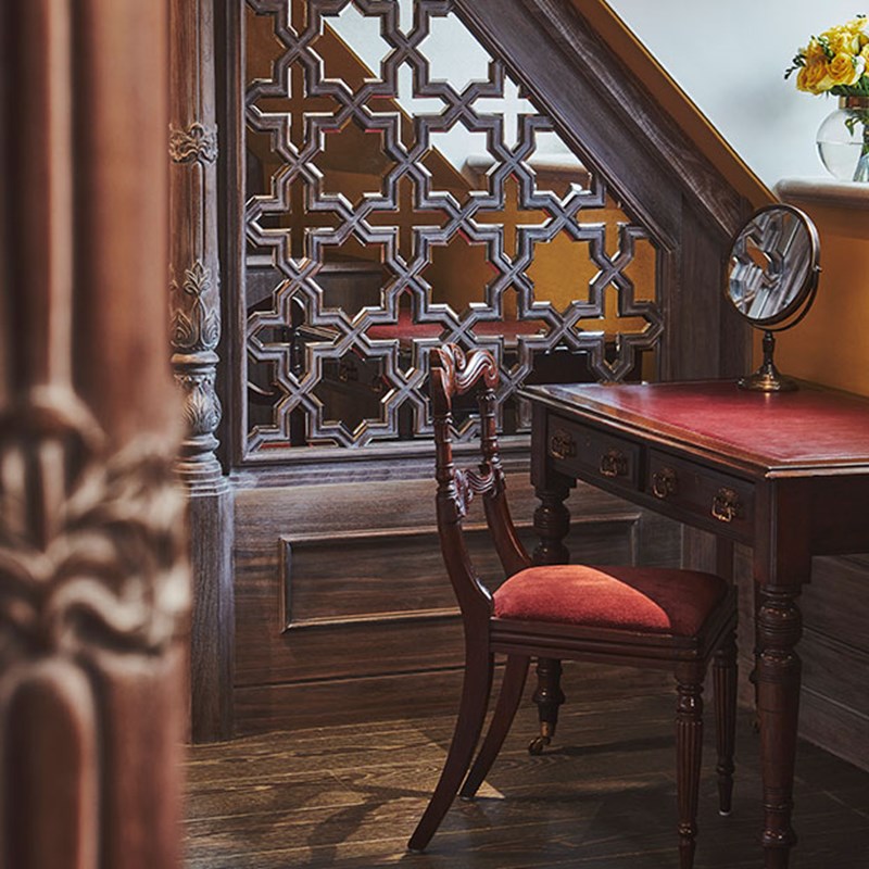 The King's Lodge at The Connaught. A wooden table and chair with a mirror placed upon it, and a wooden panel behind in a star pattern.