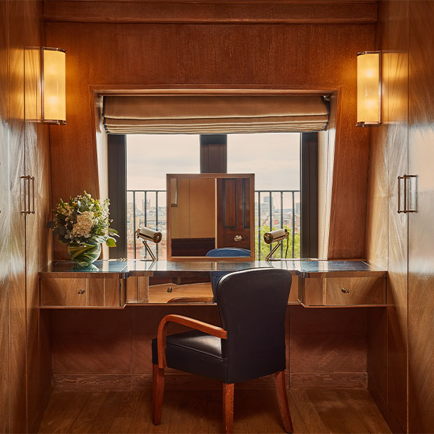 Wood-panelled dressing desk with a leather chair and window overlooking London’s skyline