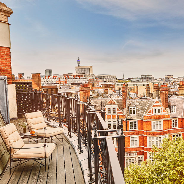 High-floor terrace with cushioned loungers overlooking red-brick rooftops and city landmarks