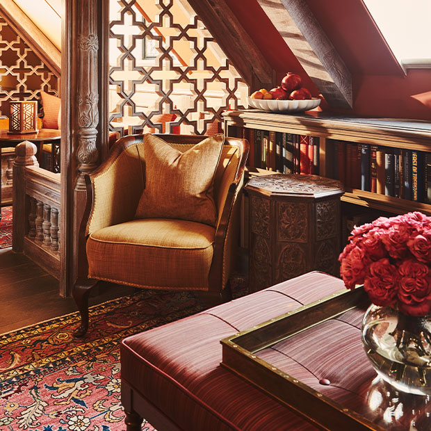 Warm reading nook with an upholstered armchair, carved wood panels and shelves of books