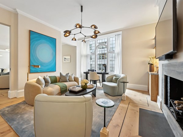 Contemporary living room with a curved sofa, modern armchairs, and a large abstract blue artwork, set beside tall windows with sheer curtains.