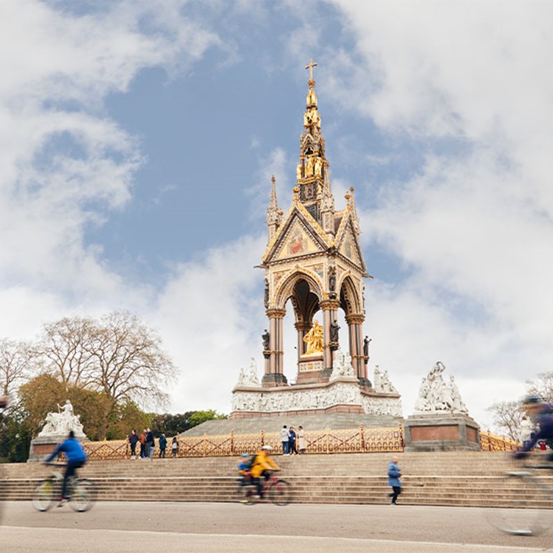 Albert Memorial with passers by walking and cycling along the path at the foot of the steps. Bare trees can be seen in the backgroud.